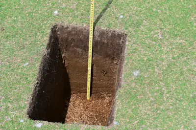 Hole dug in a golf course putting green to measure rootzone depth